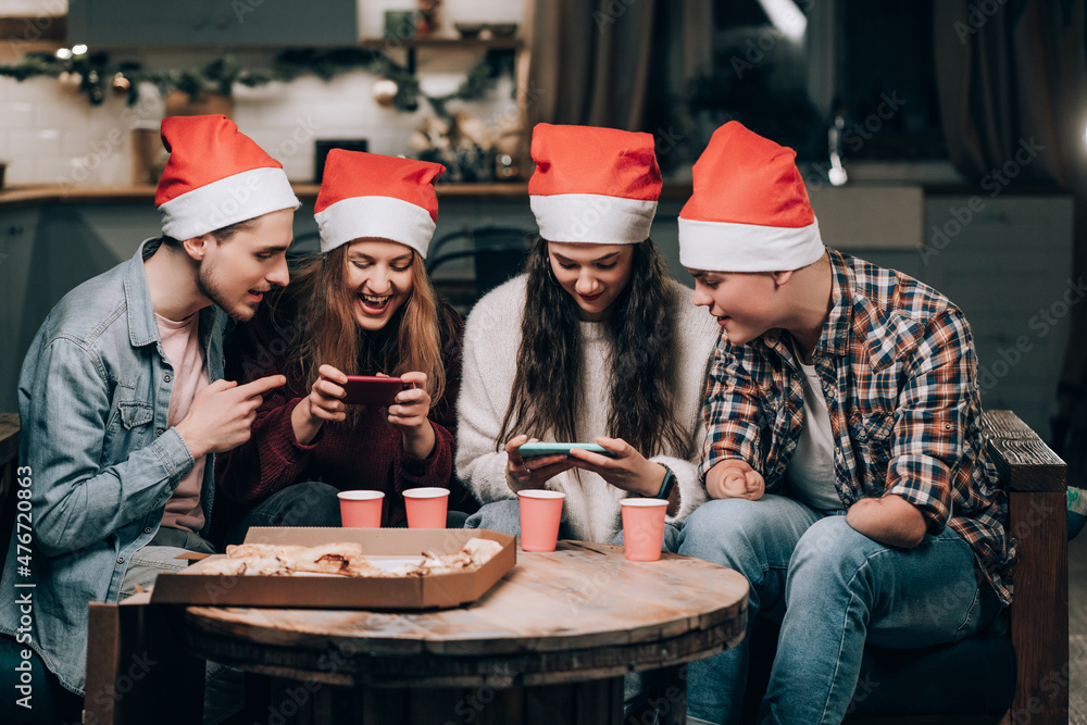 Fotka „Girls gamble on phone games, guys cheer them up. Youth New Year's  Eve party at home with pizza“ ze služby Stock | Adobe Stock