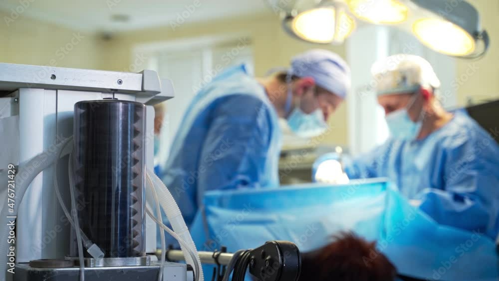 Surgical suction pump working during the operation. Tem surgeons operating at the backdrop in blur. Surgical suction pump working during the operation. Tem surgeons operating at the backdrop in blur.