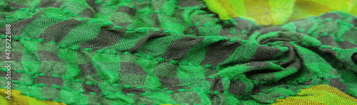 Fototapeta Naklejka Na Ścianę i Meble -  Texture, background, pattern. A woolen scarf to be worn around a person’s neck. Green black color on a scarf