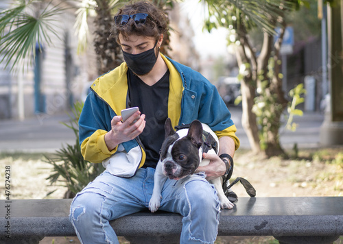 Bearded guy watching smartphone holding a French bulldog dog