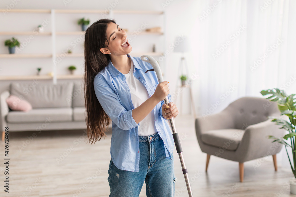 Portrait of holding woman cleaning floor singing holding mop