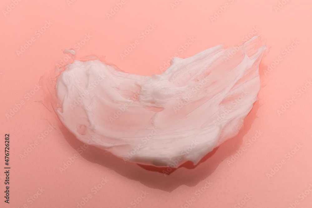 White smear of cosmetic cream isolated on pink background. Creamy foundation texture. Smear of face cream. Texture of cream background