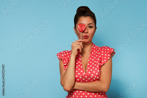 Portrait of young woman with lollipop over blue background © Gecko Studio