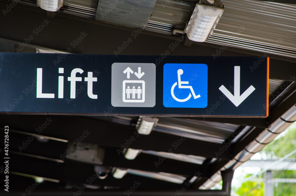A black Direction sign pointing to the lift with disabled access. A black Direction sign pointing to the lift with disabled access.