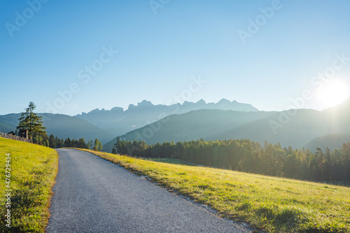 road in countryside in the dolomites mountains on a sunny early morning