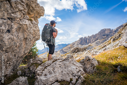 shot of a hiker with backpack from behind looking at rosengarten mountains 
