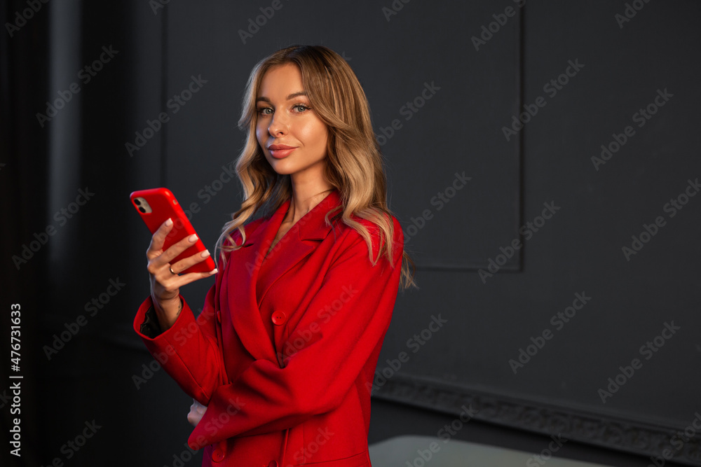 Naklejka premium beautiful caucasian businesswoman in a red suit with a phone 