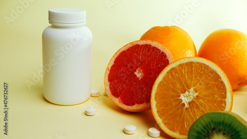 Vitamins. Medical concept. Pharmacy or natural. White bottle with vitamins, scattered pills. Juicy ripe citrus fruit slices. lemon. Orange. Grapefruit. Kiwi.
