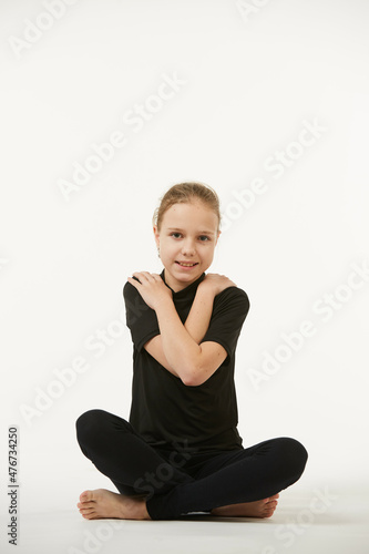 A school-age girl in black clothes stands on a white clean background.