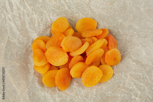 A handful of dried apricots lie on crumpled light paper