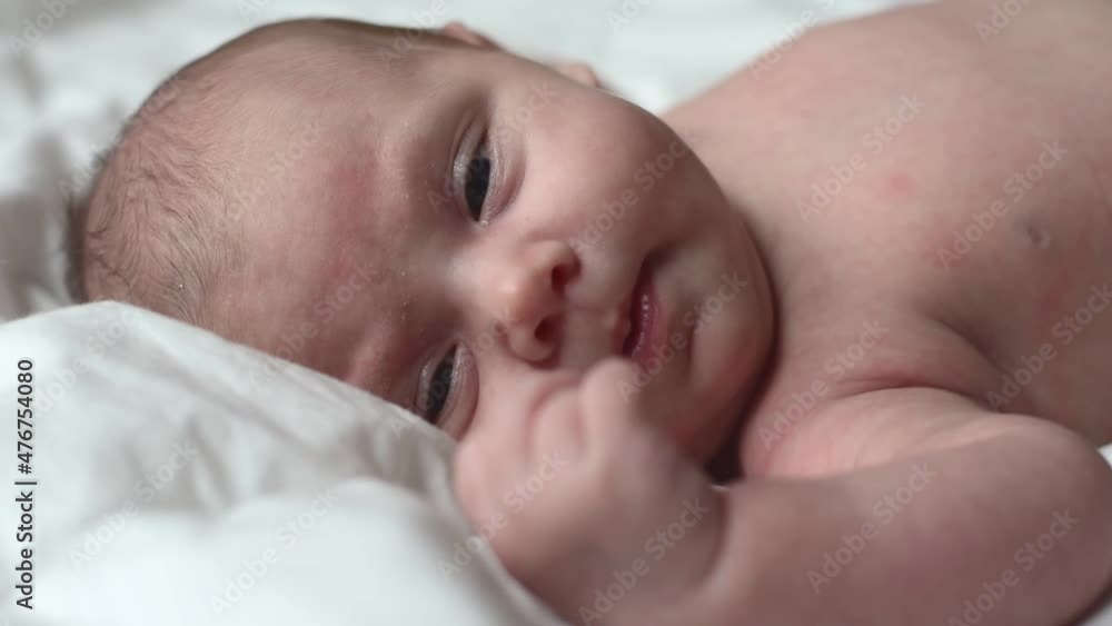 Closeup portrait of Newborn baby on white blanket. Soft focus. Infant is lying on her side. One, two week age. Infant girl waking up on bed at home. New life and growing up concept. Real People. Closeup portrait of Newborn baby on white blanket. Soft focus. Infant is lying on her side. One, two week age. Infant girl waking up on bed at home. New life and growing up concept. Real People.