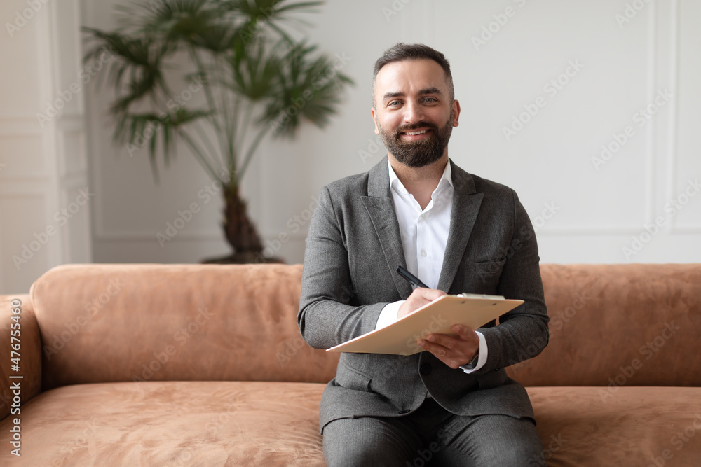 Portrait of professional male therapist in suit sitting on sofa Portrait of professional male therapist in suit sitting on sofa