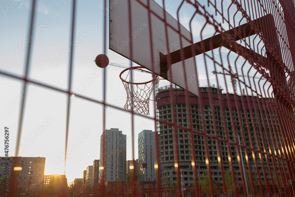 Fototapeta premium basketball flying in the rim with net of a board on buildings background. Tyufeleva Roshcha park, Zilart. !melk landscape architecture urban design