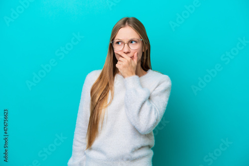 Young Russian woman isolated on blue background having doubts and with confuse face expression