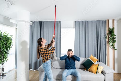 Young couple stares at the ceiling and yells because a neighbor upstairs is having a party with loud music or renovating an apartment and workers are drilling with heavy tools. Nise pollution concept photo