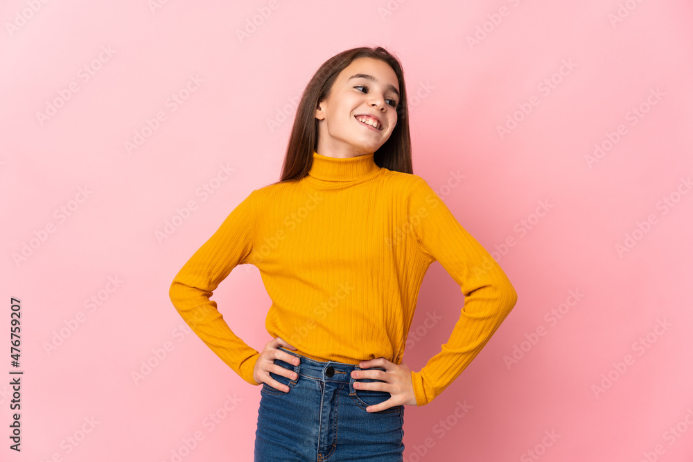 Little girl isolated on pink background posing with arms at hip and smiling Little girl isolated on pink background posing with arms at hip and smiling