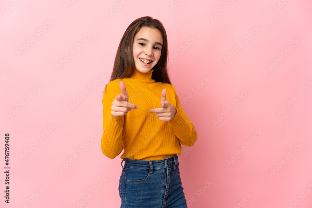 Little girl isolated on pink background pointing to the front and smiling Little girl isolated on pink background pointing to the front and smiling