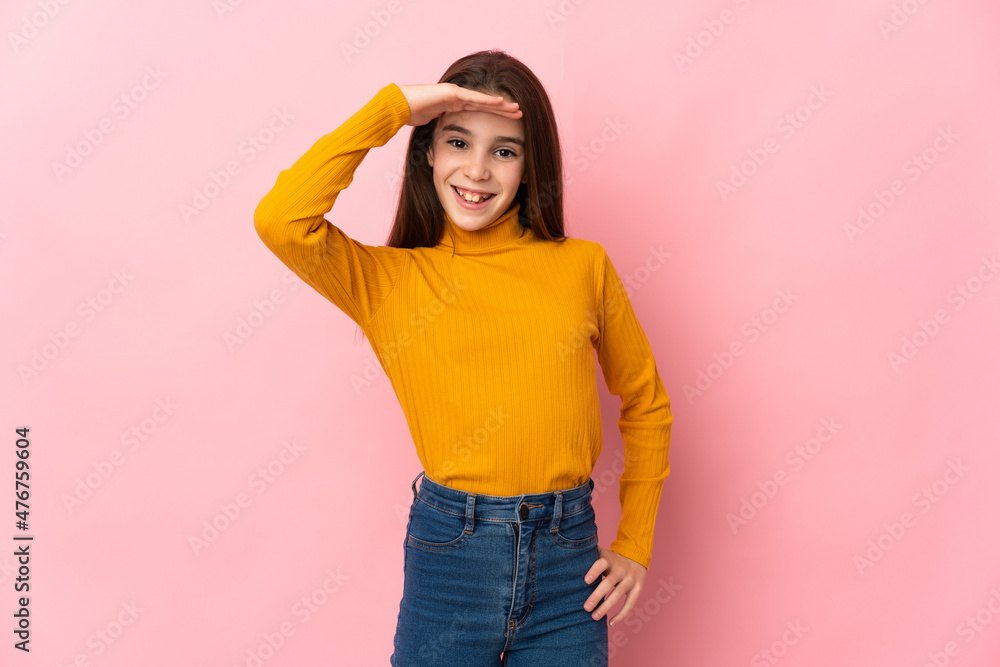 Little girl isolated on pink background looking far away with hand to look something Little girl isolated on pink background looking far away with hand to look something