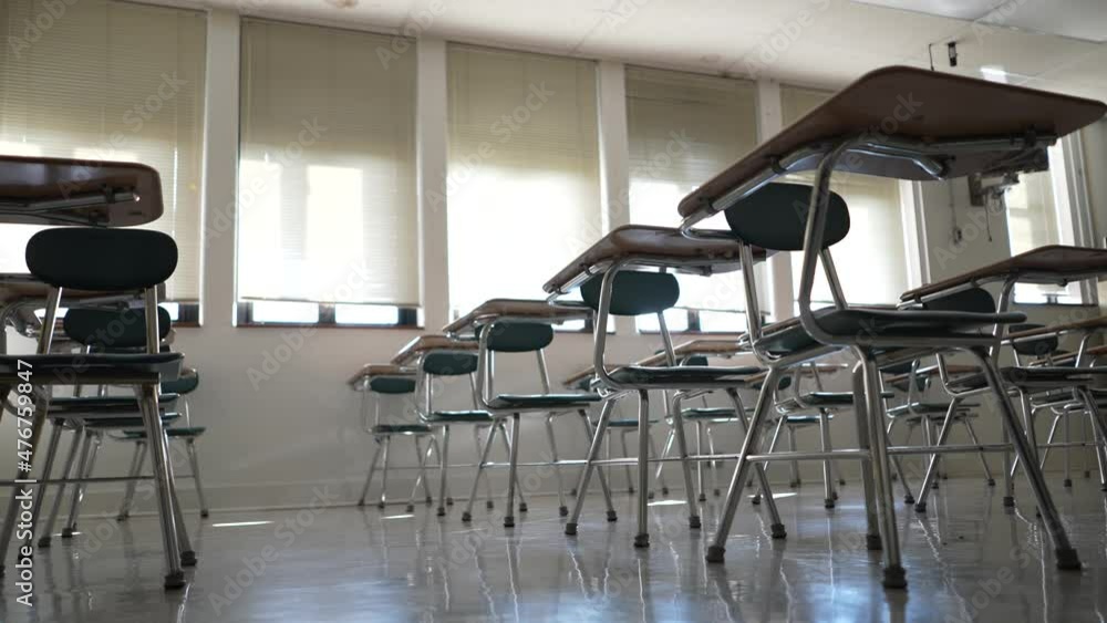 Desks in empty dark high, middle, or elementary school classroom with light coming through windows. Desks in empty dark high, middle, or elementary school classroom with light coming through windows.