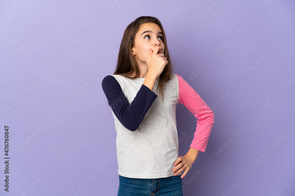 Little girl isolated on purple background having doubts and with confuse face expression Little girl isolated on purple background having doubts and with confuse face expression