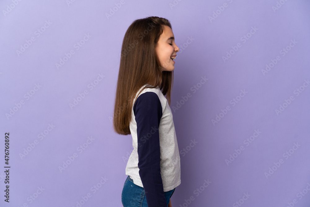Little girl isolated on purple background laughing in lateral position Little girl isolated on purple background laughing in lateral position