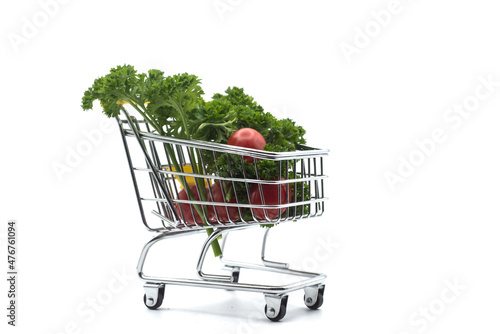Closeup of fresh vegetables in a miniature trolley of supermarket on white background