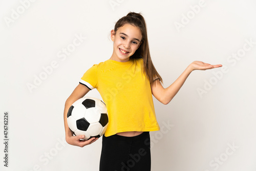 Little football player girl isolated on white background extending hands to the side for inviting to come