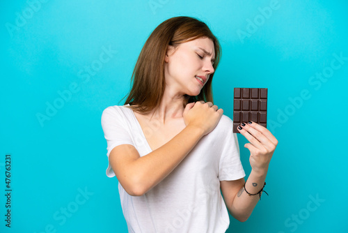 Young English woman with chocolat isolated on blue background suffering from pain in shoulder for having made an effort
