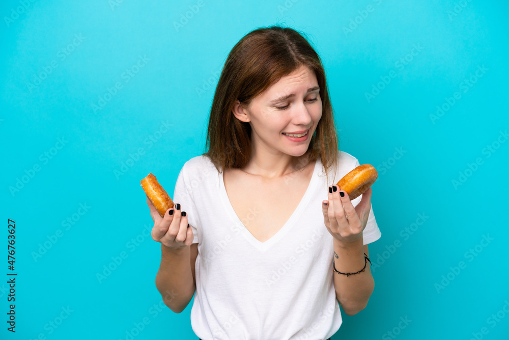 Young English woman isolated on blue background holding donuts with happy expression Young English woman isolated on blue background holding donuts with happy expression