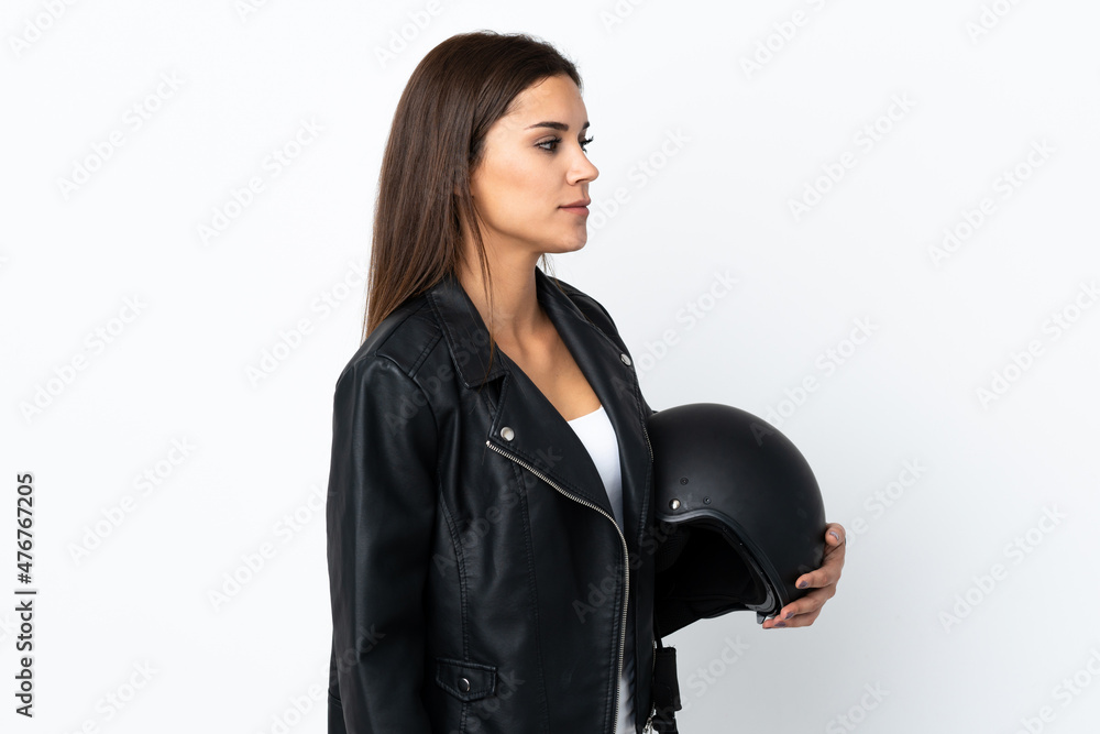 Caucasian girl holding a motorcycle helmet on white background looking to the side Caucasian girl holding a motorcycle helmet on white background looking to the side