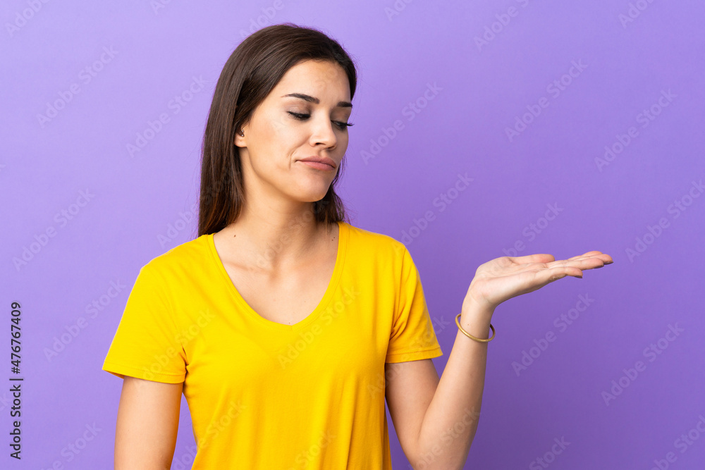 Young caucasian woman over isolated background holding copyspace with doubts Young caucasian woman over isolated background holding copyspace with doubts