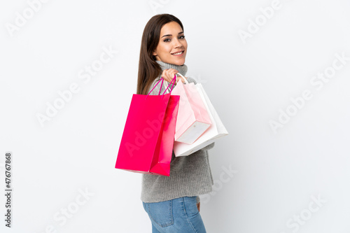 Young caucasian woman isolated on white background holding shopping bags and smiling