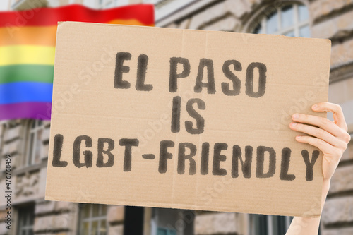 The phrase " El Paso is LGBT-Friendly " on a banner in men's hand with blurred LGBT flag on the background. Human relationships. different. Diverse. liberty. Sexuality. Social issues. Society