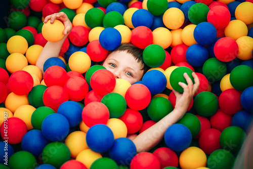 A teenage boy, an infante lies buried in balloons in a dry pool, the child is almost invisible among the colorful balloons. A holiday in the entertainment center.