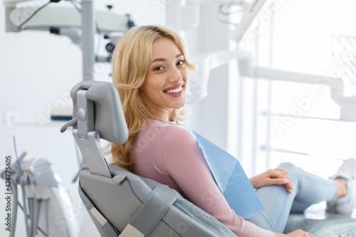 Smiling and relaxed young woman sitting at dental chair