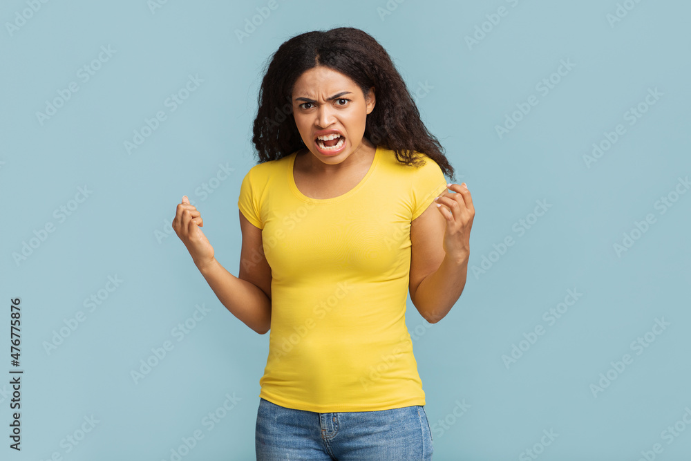 Furious african american woman screaming out loud, expressing negative emotions and clenching her fists Furious african american woman screaming out loud, expressing negative emotions and clenching her fists