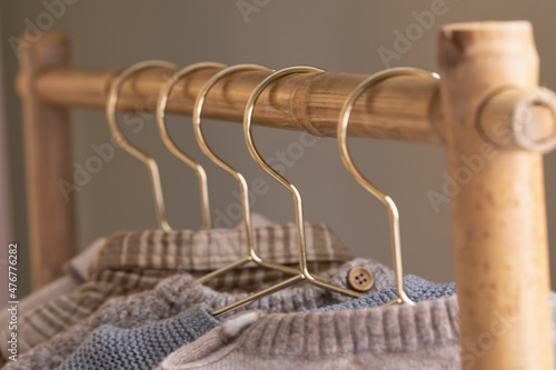 Baby clothes collection hanging on a wooden clothing rack on golden clothes hangers