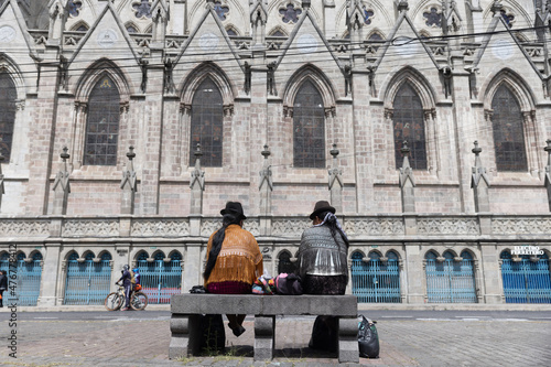 Two Indigenous Quechua women sitting in front of Cathedral in Quito Ecuador photo