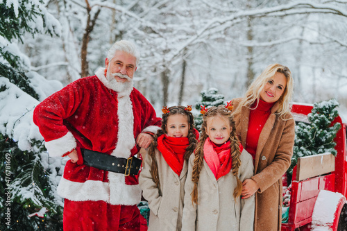 Beautiful mom and two daughters stand next to Santa Claus near a red pickup in the snow. High quality FullHD footage