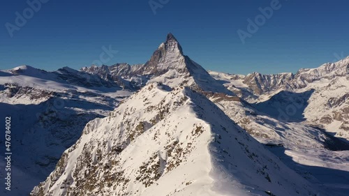 Aerial drone footage of the Matterhorn and the gornergrat ridge with its observatory and hotel above Zermatt in the alps in Switzerland on a sunny winter day.  photo