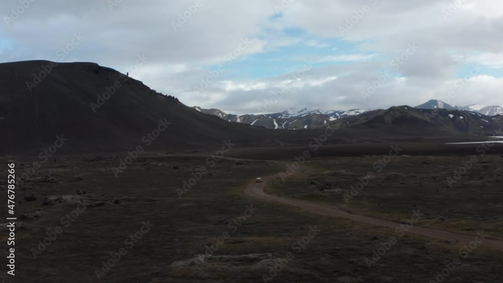 High angle view panorama of 4x4 vehicle driving offroad stony terrain exploring wilderness of icelandic highlands. Top view Skaftafell national park with snowy mountains and green moss countryside High angle view panorama of 4x4 vehicle driving offroad stony terrain exploring wilderness of icelandic highlands. Top view Skaftafell national park with snowy mountains and green moss countryside
