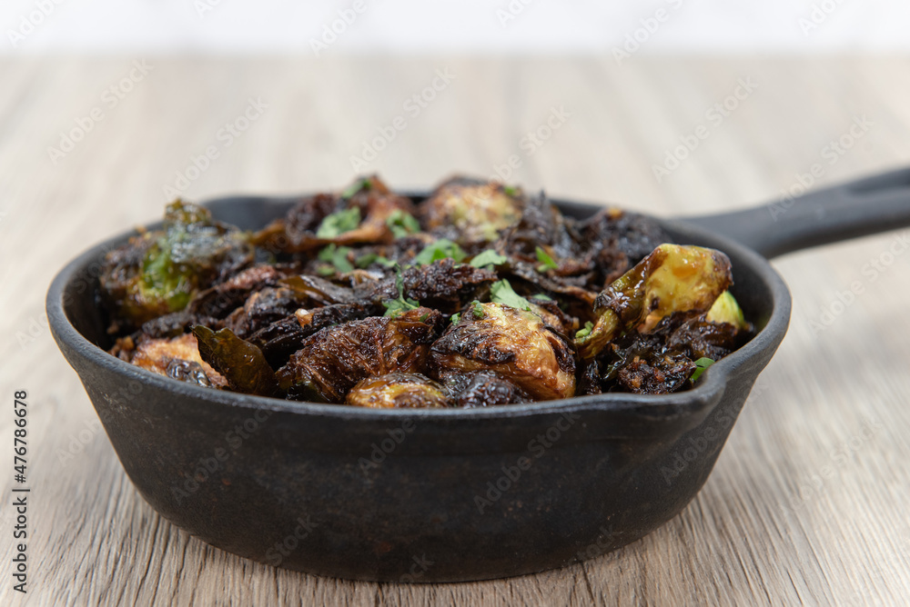 Crispy baked brussel sprouts served as finger food to be eaten out of cast iron pan Crispy baked brussel sprouts served as finger food to be eaten out of cast iron pan