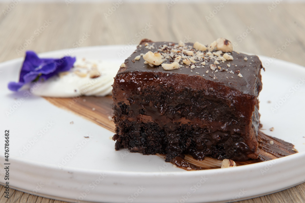 Sweet treat dessert for after dinner includes a rich piece of chocolate cake topped with crushed nuts Sweet treat dessert for after dinner includes a rich piece of chocolate cake topped with crushed nuts