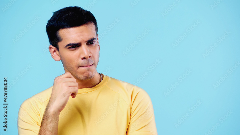 Fototapeta premium thoughtful young man in yellow t-shirt thinking isolated on blue.