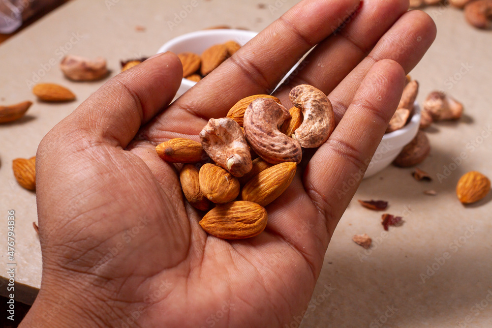 Roasted almond and cashew nuts in hand on light background isolation. Roasted almond and cashew nuts in hand on light background isolation.