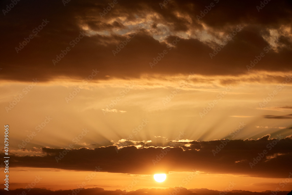 Background of a warm sun between clouds with sunbeams at sunset Background of a warm sun between clouds with sunbeams at sunset