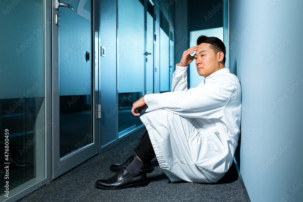 Upset and thinking asian man sitting on the floor in the laboratory, frustrated scientist Upset and thinking asian man sitting on the floor in the laboratory, frustrated scientist