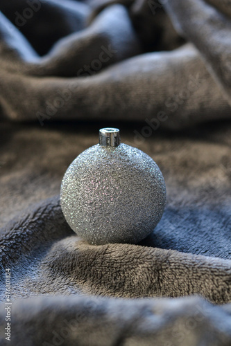 Silver Christmas ball ornament on a grey blanket