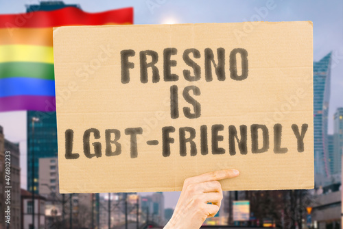 Wallpaper Mural The phrase " Fresno is LGBT-Friendly " on a banner in men's hand with blurred LGBT flag on the background. Human relationships. different. Diverse. liberty. Sexuality. Social issues. Society Torontodigital.ca
