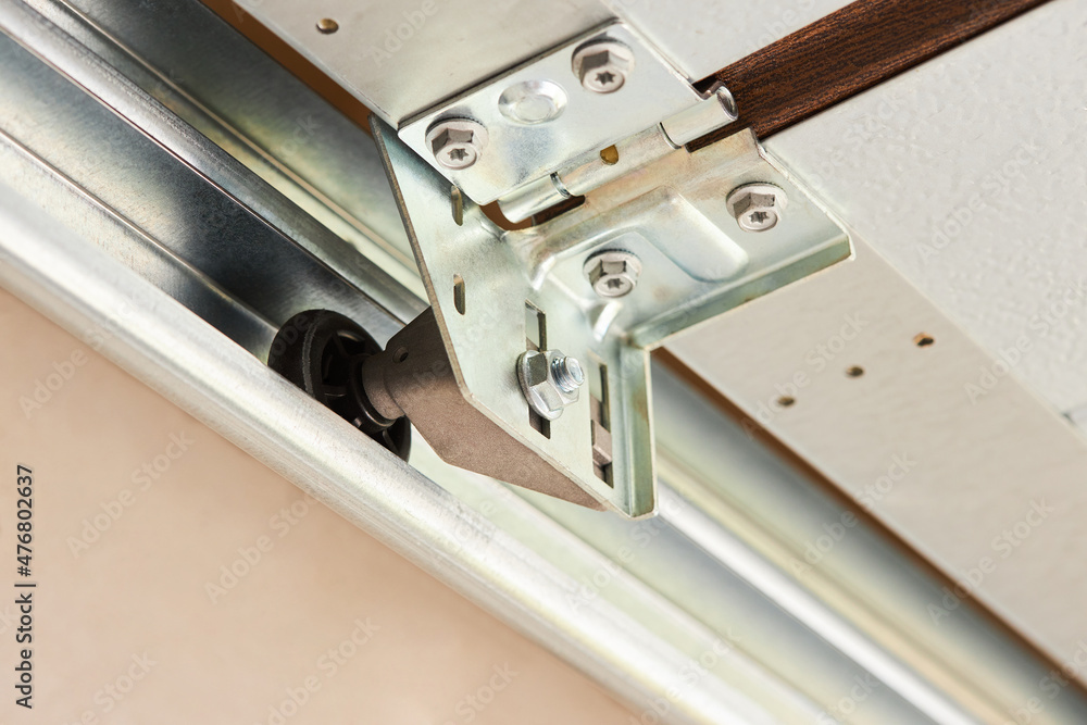 Automatic Garage Door mechanism close up. Lifting gates of the garage. Metal wheel, Springs tensioning, handle, fastening of a garage door. Automatic Garage Door mechanism close up. Lifting gates of the garage. Metal wheel, Springs tensioning, handle, fastening of a garage door.